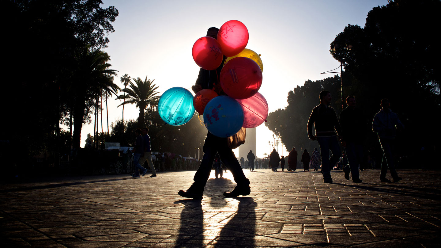 man with balloons in sunset city street